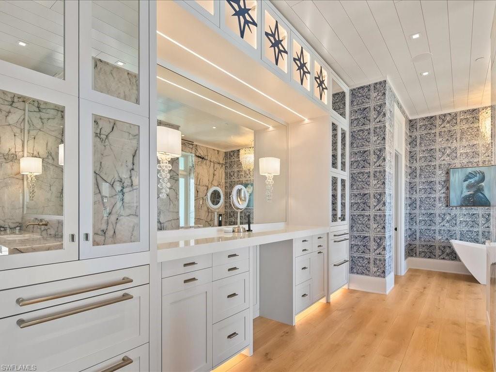 Luxury bathroom with a long white vanity, patterned blue-gray tile walls, and a freestanding bathtub.
