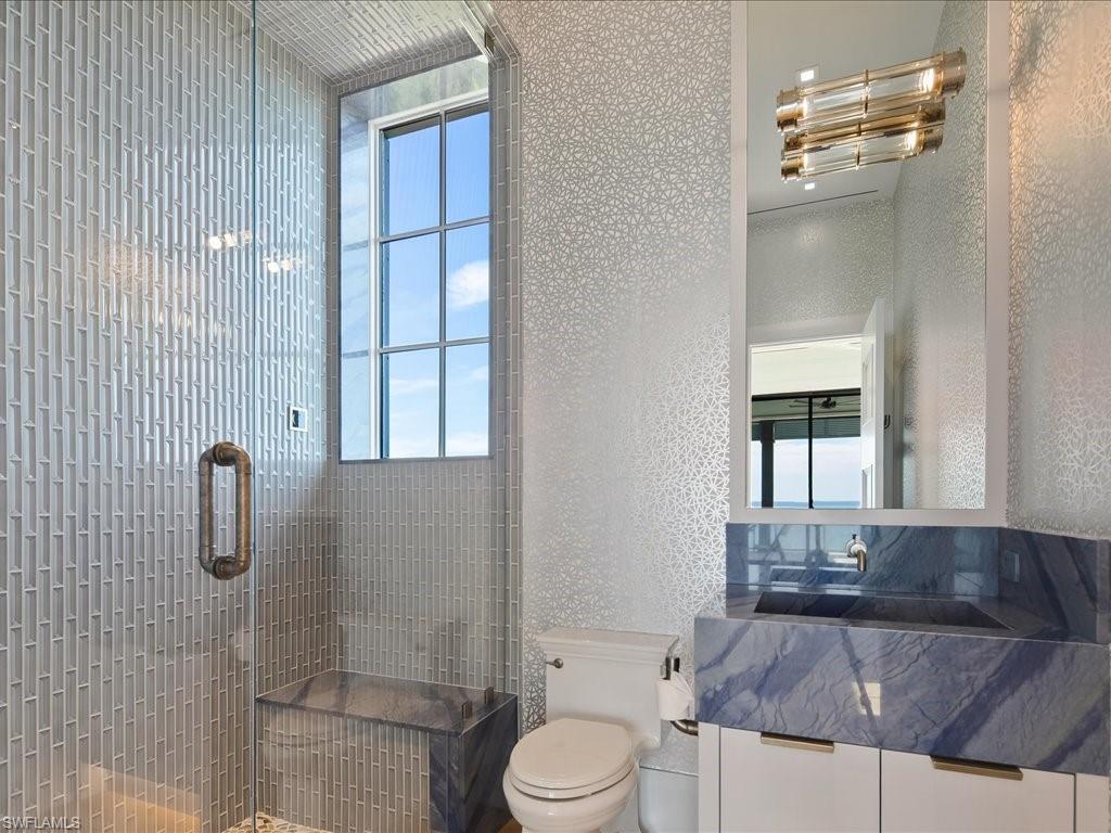 Modern bathroom with a tall shower window, gray tile, and a blue-gray marble vanity.