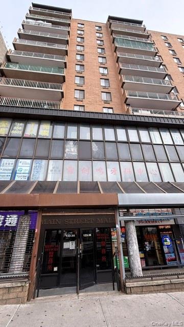 Brick apartment building with stacked balconies above Main Street Mall storefronts and a pharmacy.