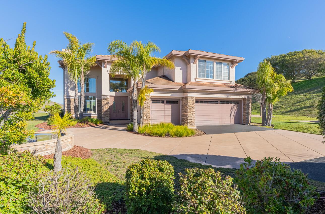 Two-story home with stone accents, palm trees, and a three-car garage.
