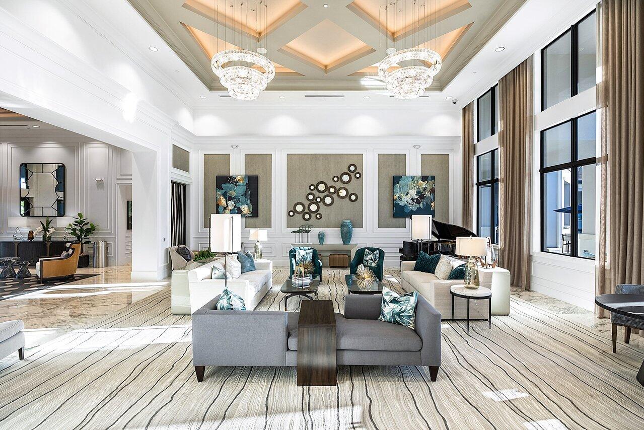 Elegant living room with twin crystal chandeliers, tall windows, and marble floors.