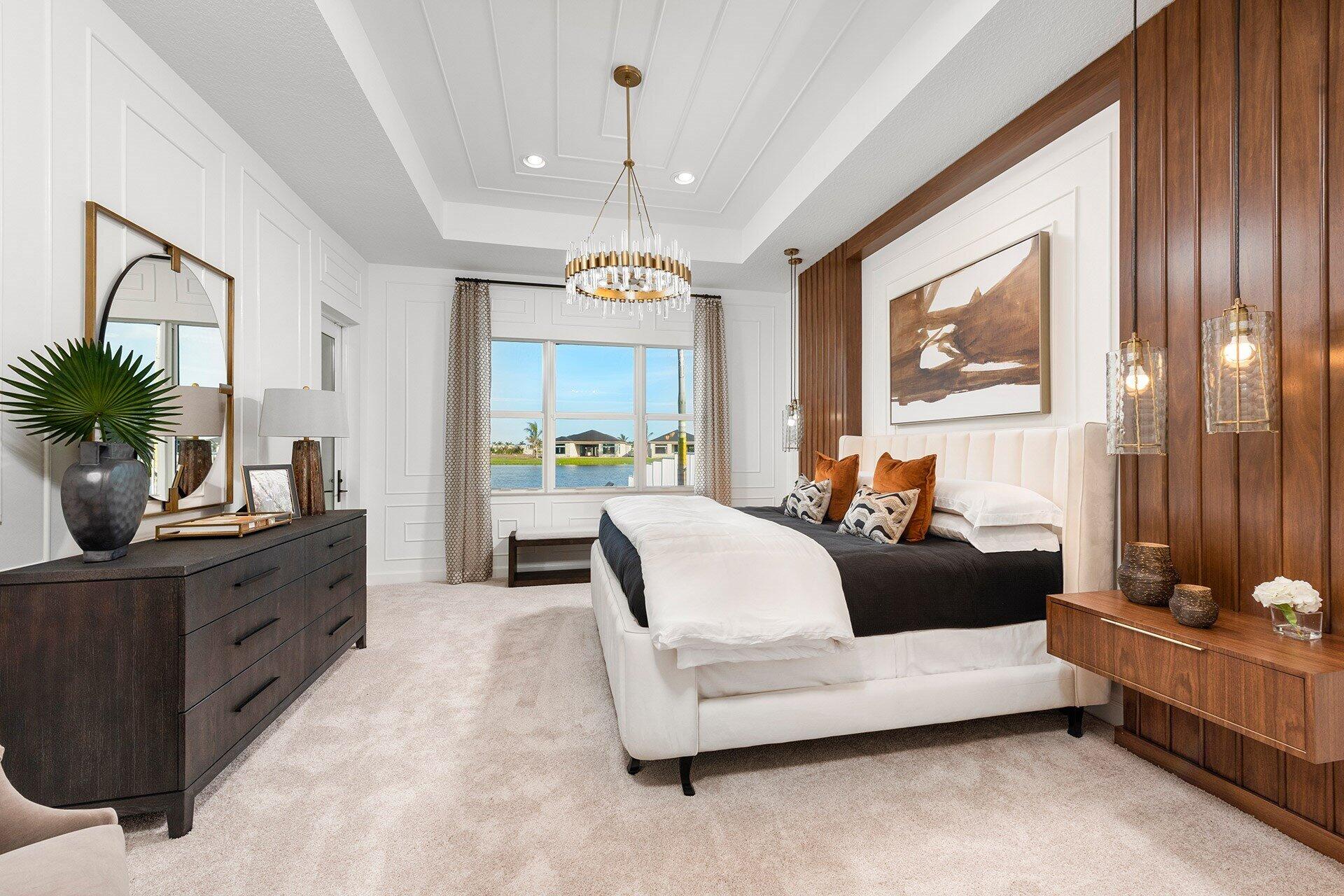 Bedroom with a white bed, wood accent wall, and large windows overlooking the water.