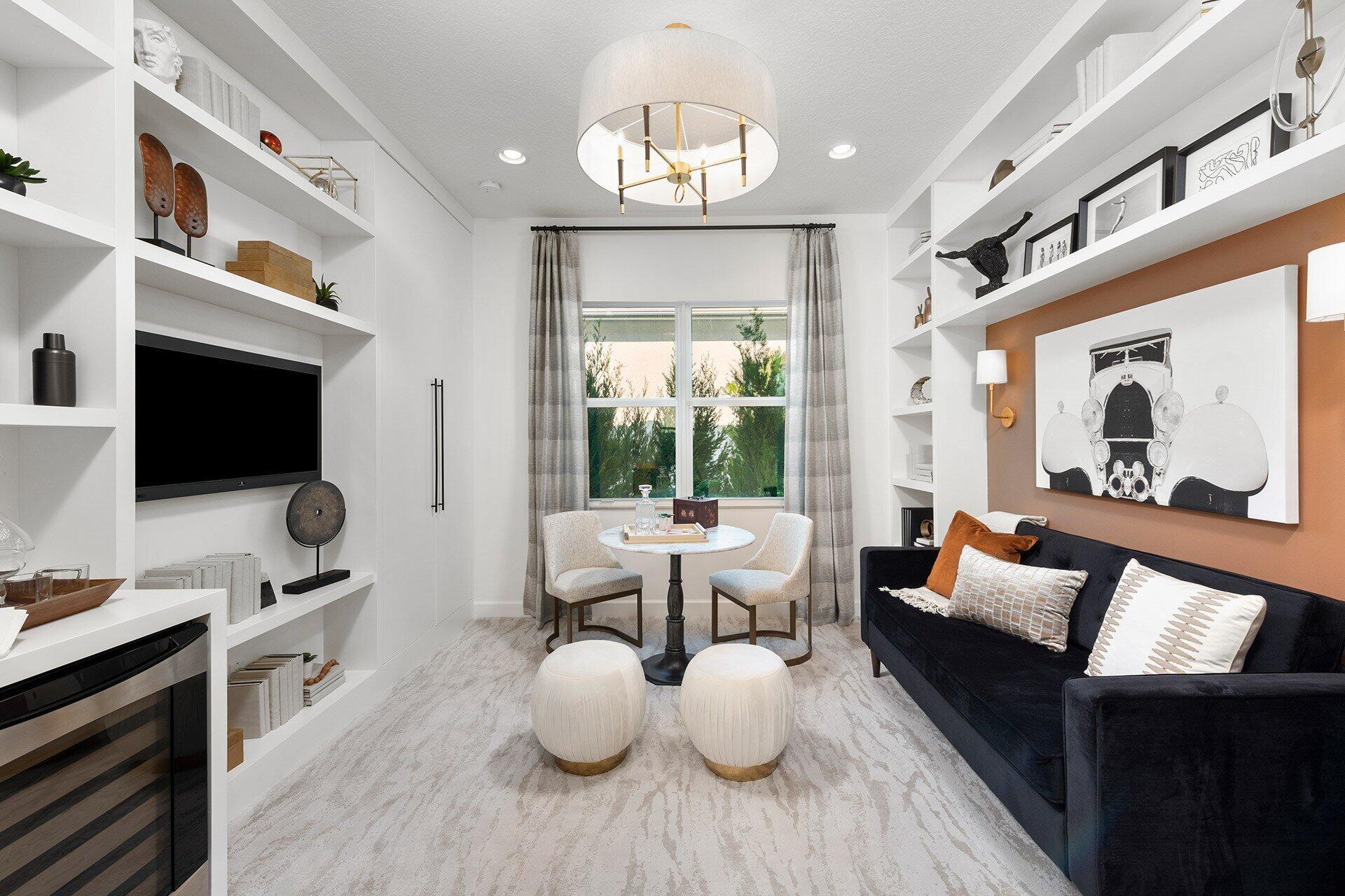 Sitting room with built-in shelves, a navy sofa, and a small table beside the window.