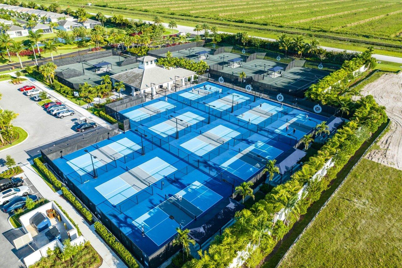 Pickleball courts in a residential community, with a clubhouse and open fields nearby.