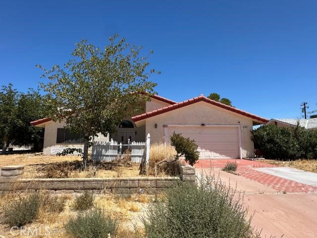 Single-story stucco house with a red tile roof, attached garage, and dry front yard.
