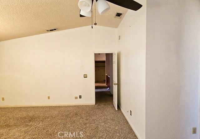 Empty carpeted bedroom with a ceiling fan and an open doorway.
