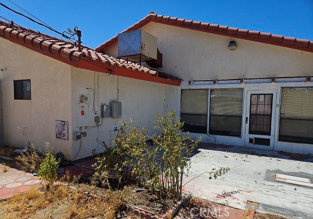 Home exterior with red tile roof, paved patio, and glass-paneled entry door.