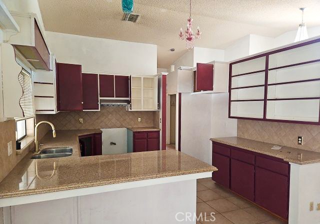 Kitchen with burgundy cabinets, granite counters, and a breakfast bar.