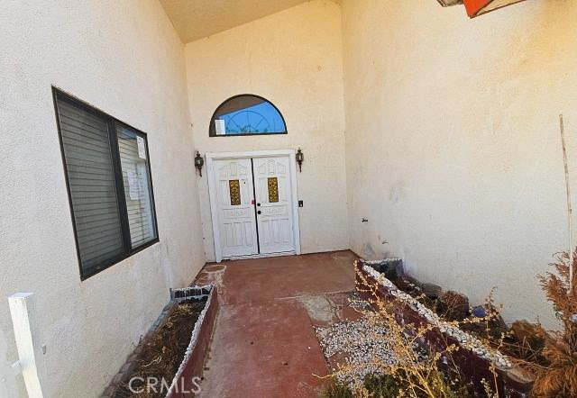 Covered home entry with white double doors, an arched transom window, and a reddish walkway.