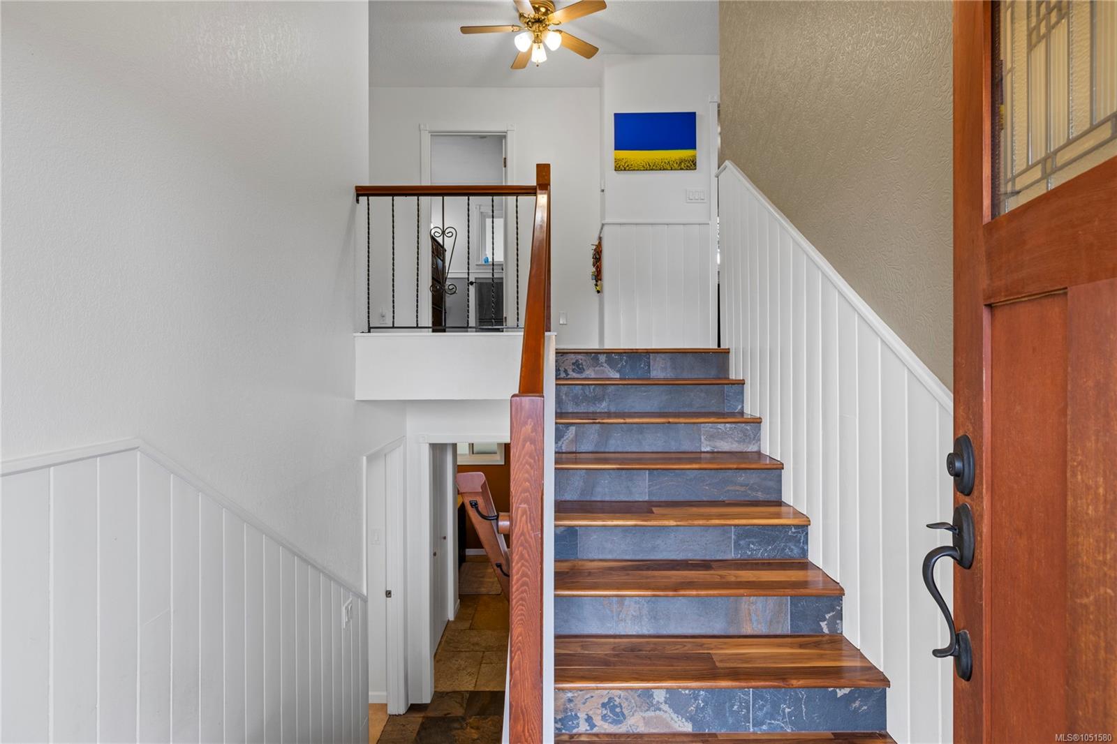 Entry foyer with a wood-tread staircase, blue stone risers, and an open landing.