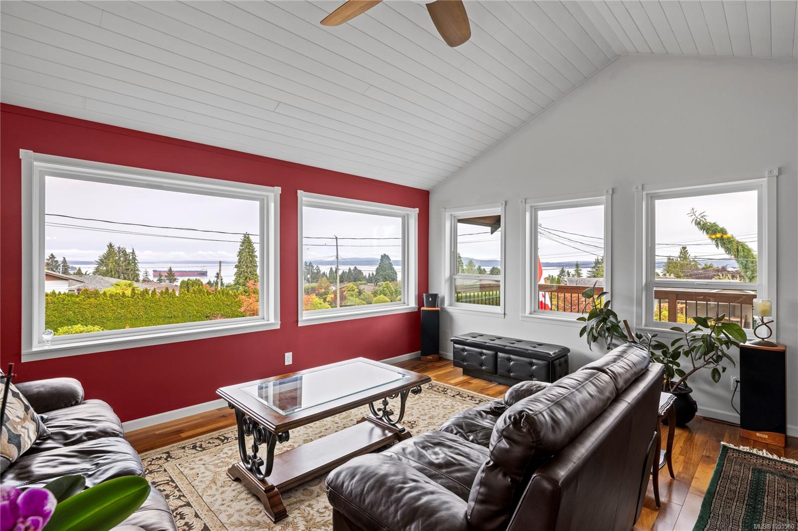 Living room with leather sofas, a vaulted ceiling, and ocean views through wide windows.