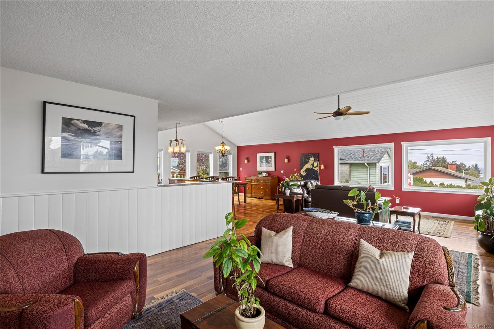 Furnished living room with burgundy sofas, a red accent wall, and hardwood floors.