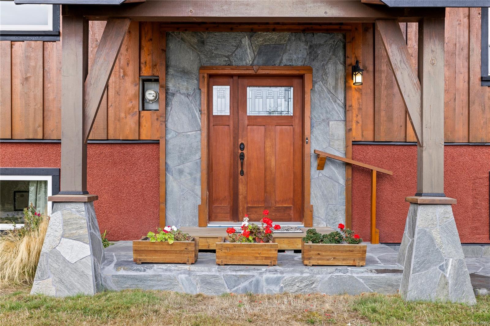 Front entrance with a wooden double door, stone surround, and flower planters.