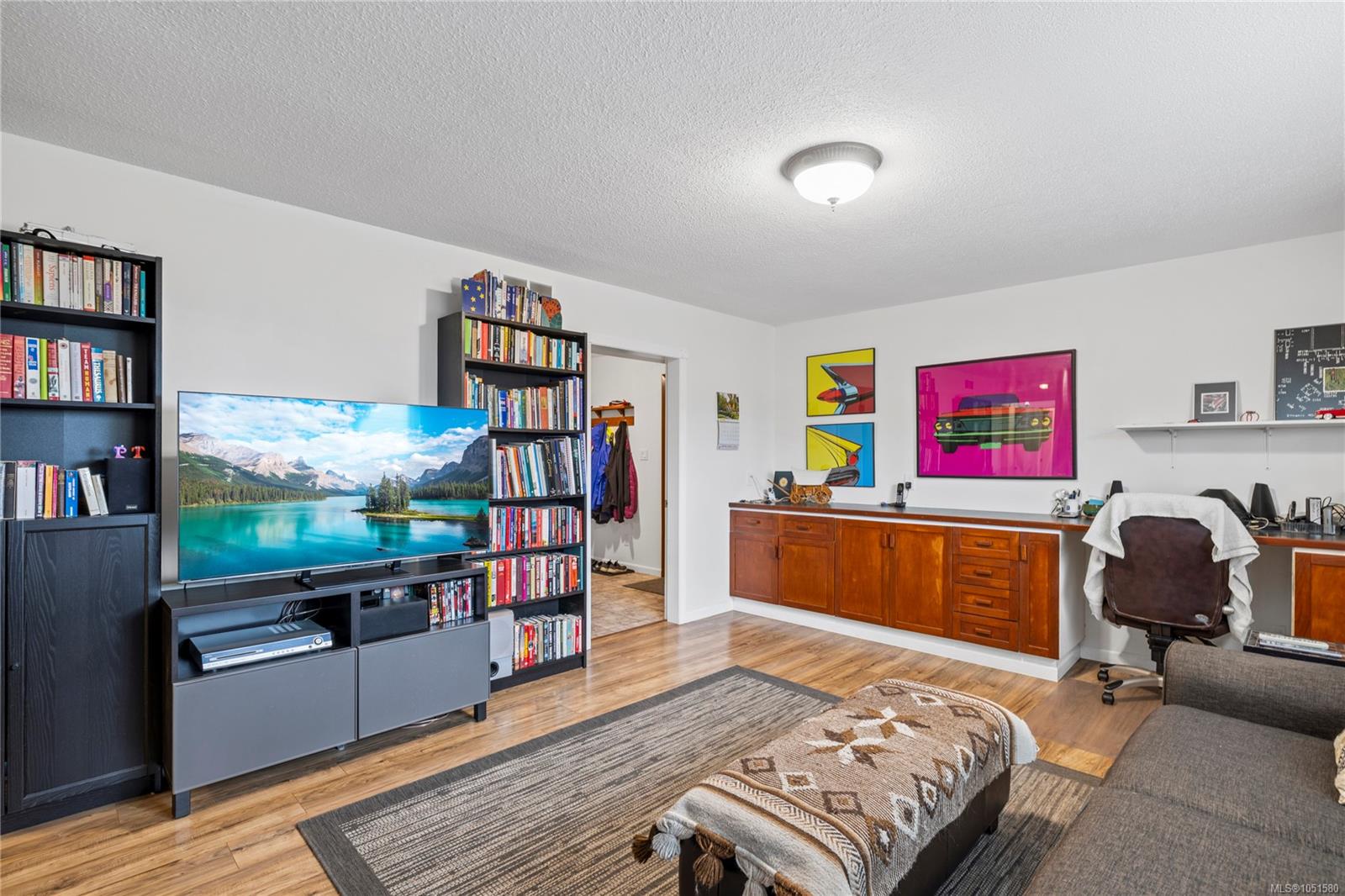Home office with built-in desk, bookshelves, television, and seating area.