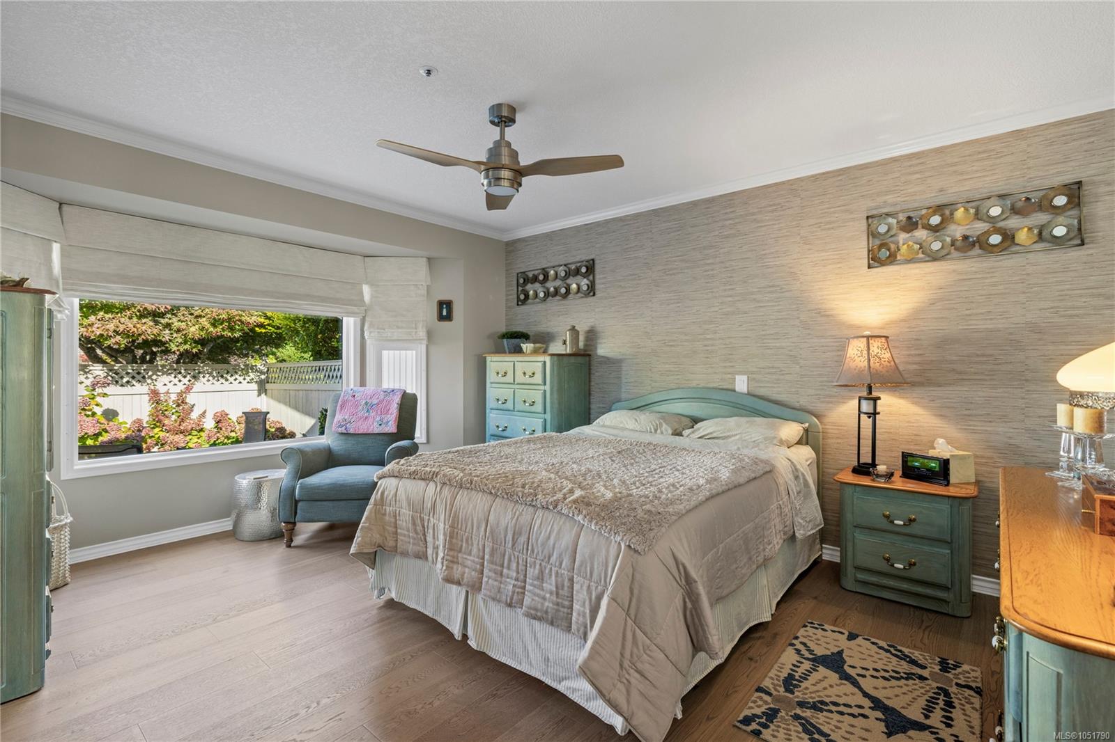 Furnished bedroom with a large bed and wide garden-view window.