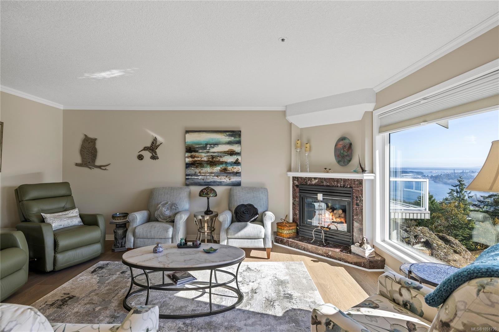 Living room with a fireplace, seating area, and large windows overlooking the water.