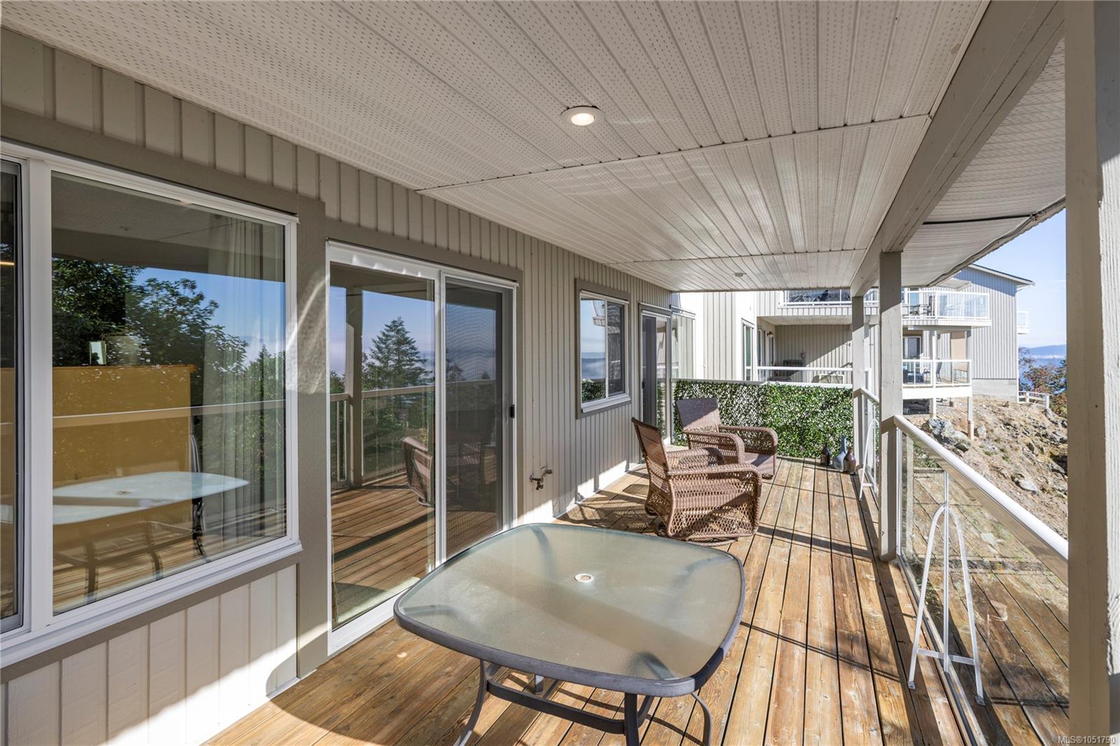 Covered wood deck with patio seating and a water view.