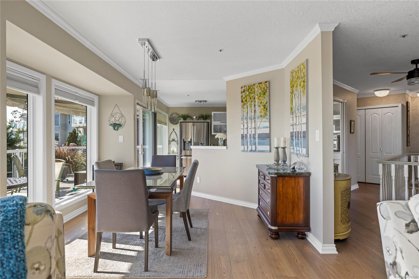 Dining area with a glass table beside large windows, opening onto the kitchen and hallway.