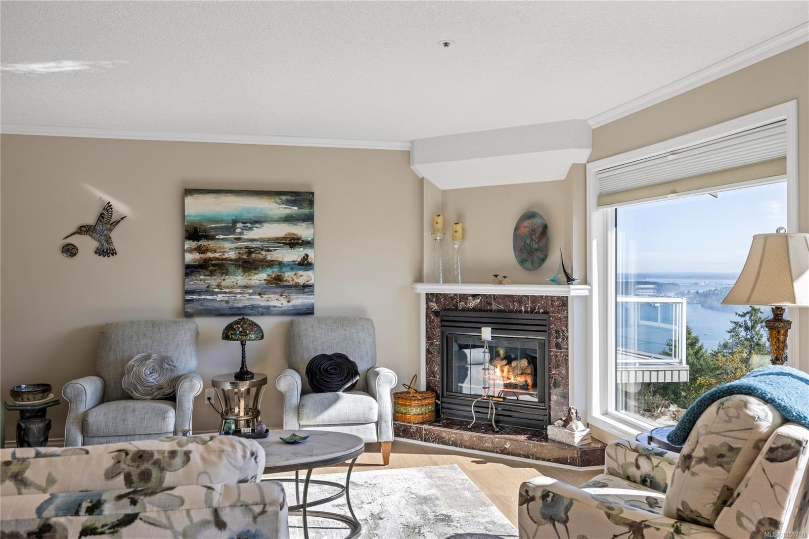 Living room with a stone-framed fireplace and a large window overlooking the water.