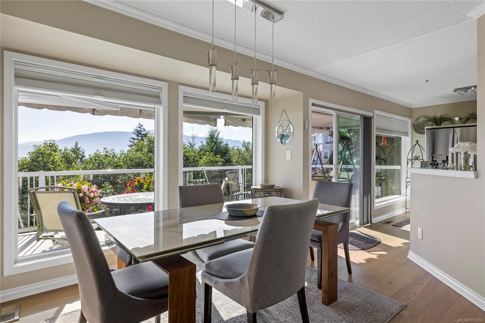 Dining room with a glass-top table, large windows, and distant mountain views.