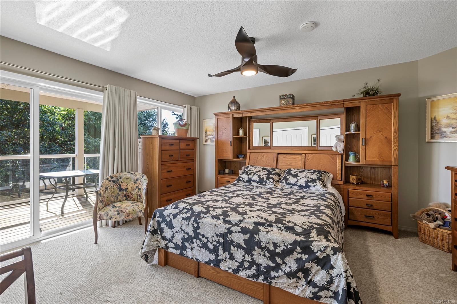 Bedroom with a wooden bed, floral bedding, and sliding doors opening onto a covered deck.