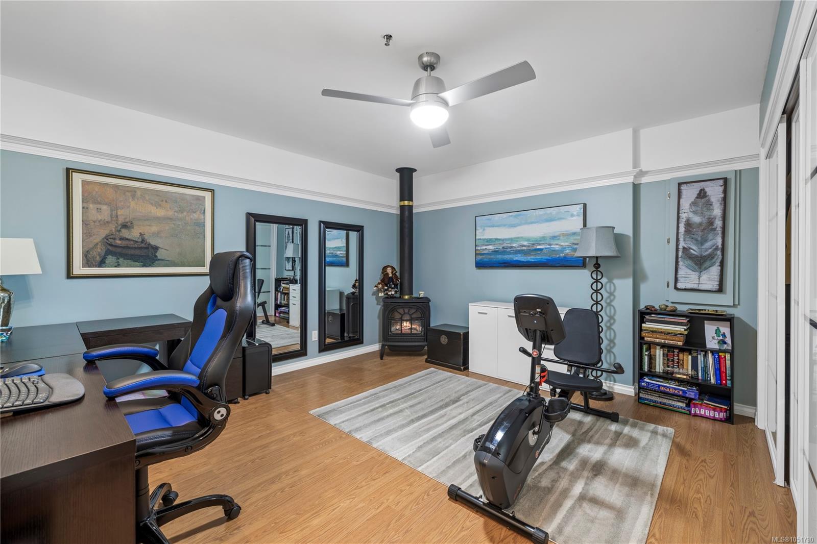 Home office and workout room with an exercise bike, desk, and freestanding wood stove.