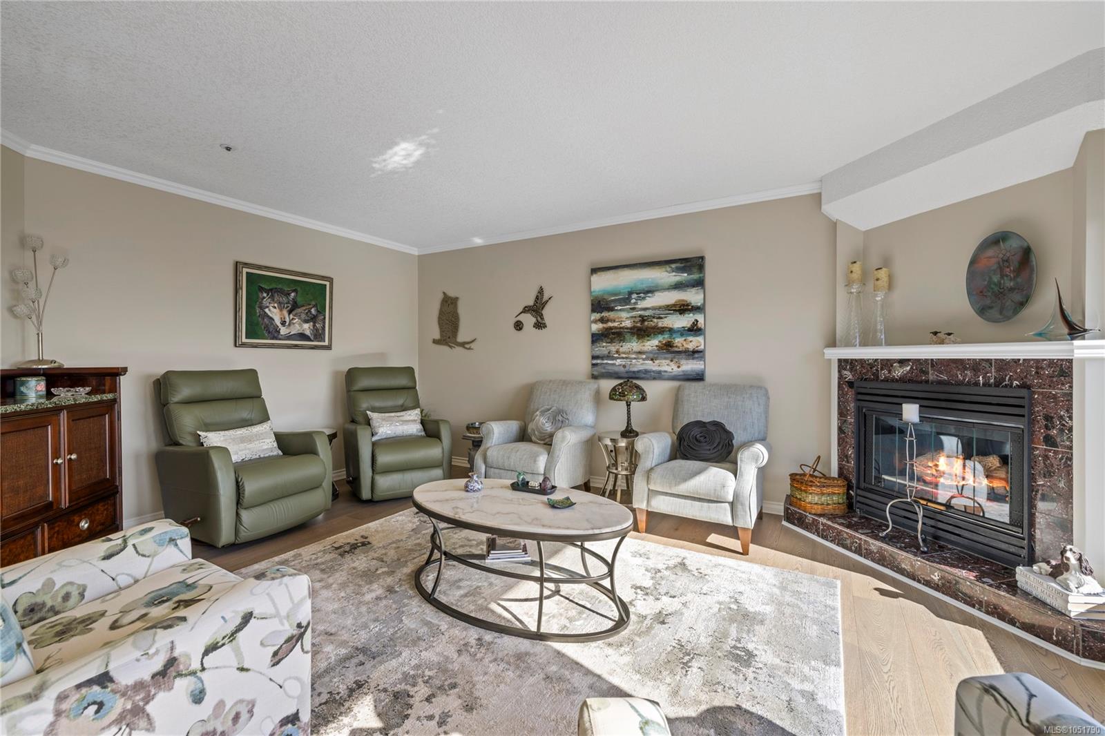 Living room with green recliners, pale armchairs, and a lit fireplace.
