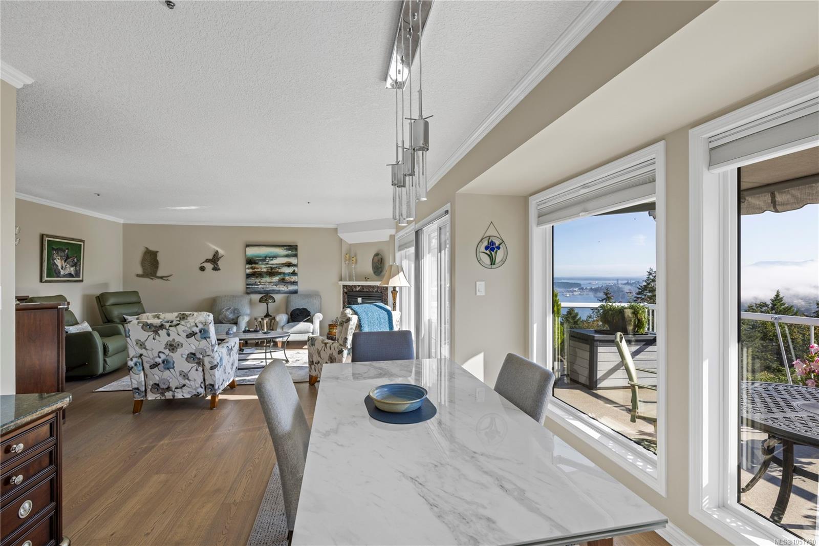 Open-plan living and dining room with large windows overlooking water and a sunny deck.