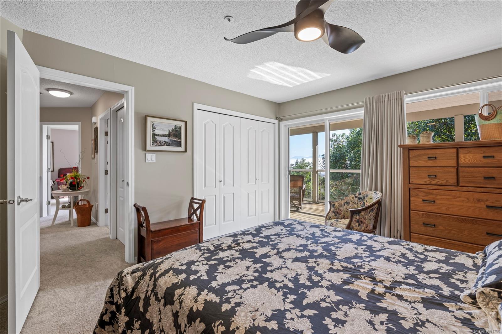 Bedroom with floral bedspread and sliding doors opening to a deck with a water view.