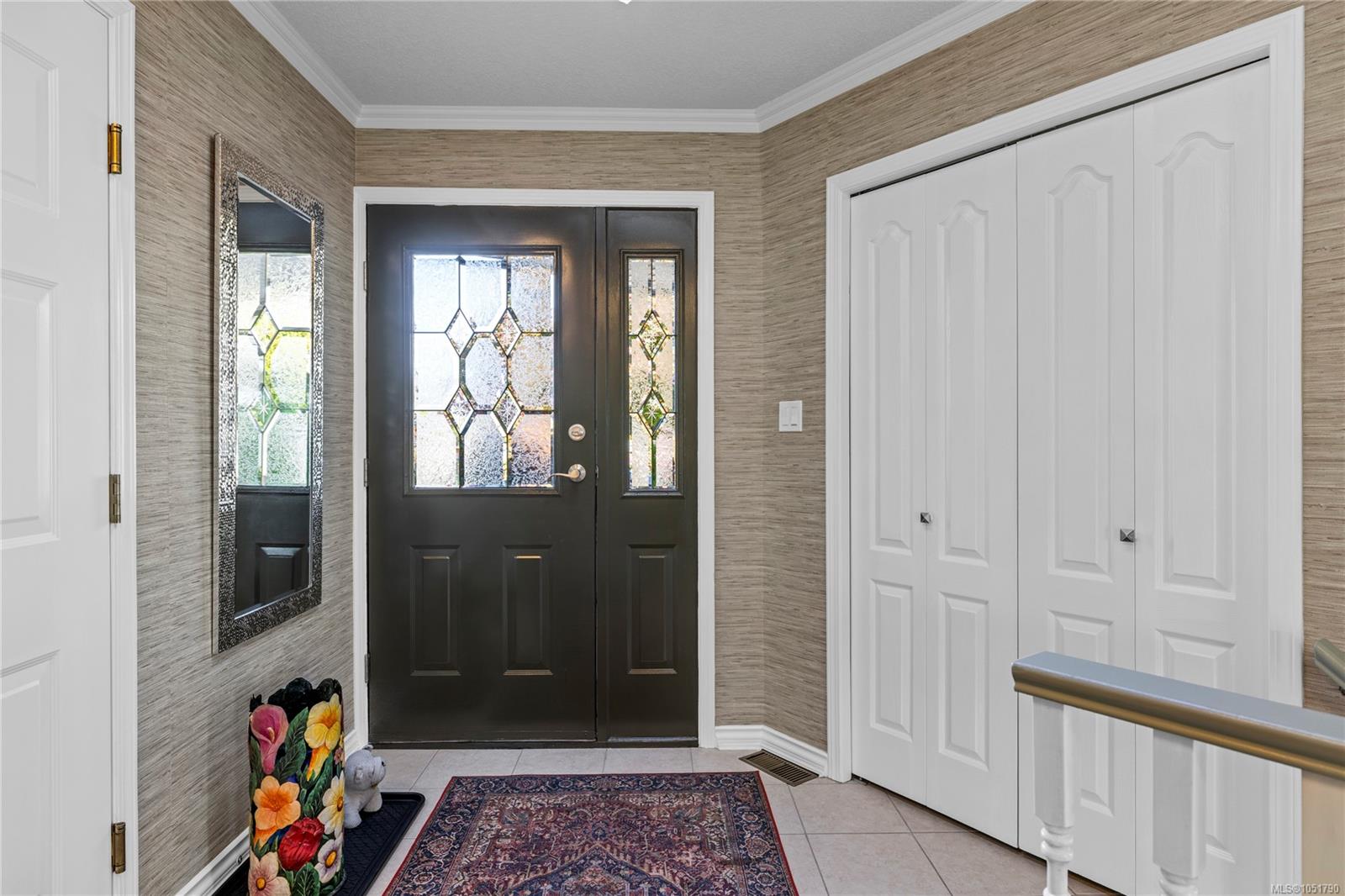 Entry foyer with a dark decorative-glass front door, white closets, and patterned rugs.