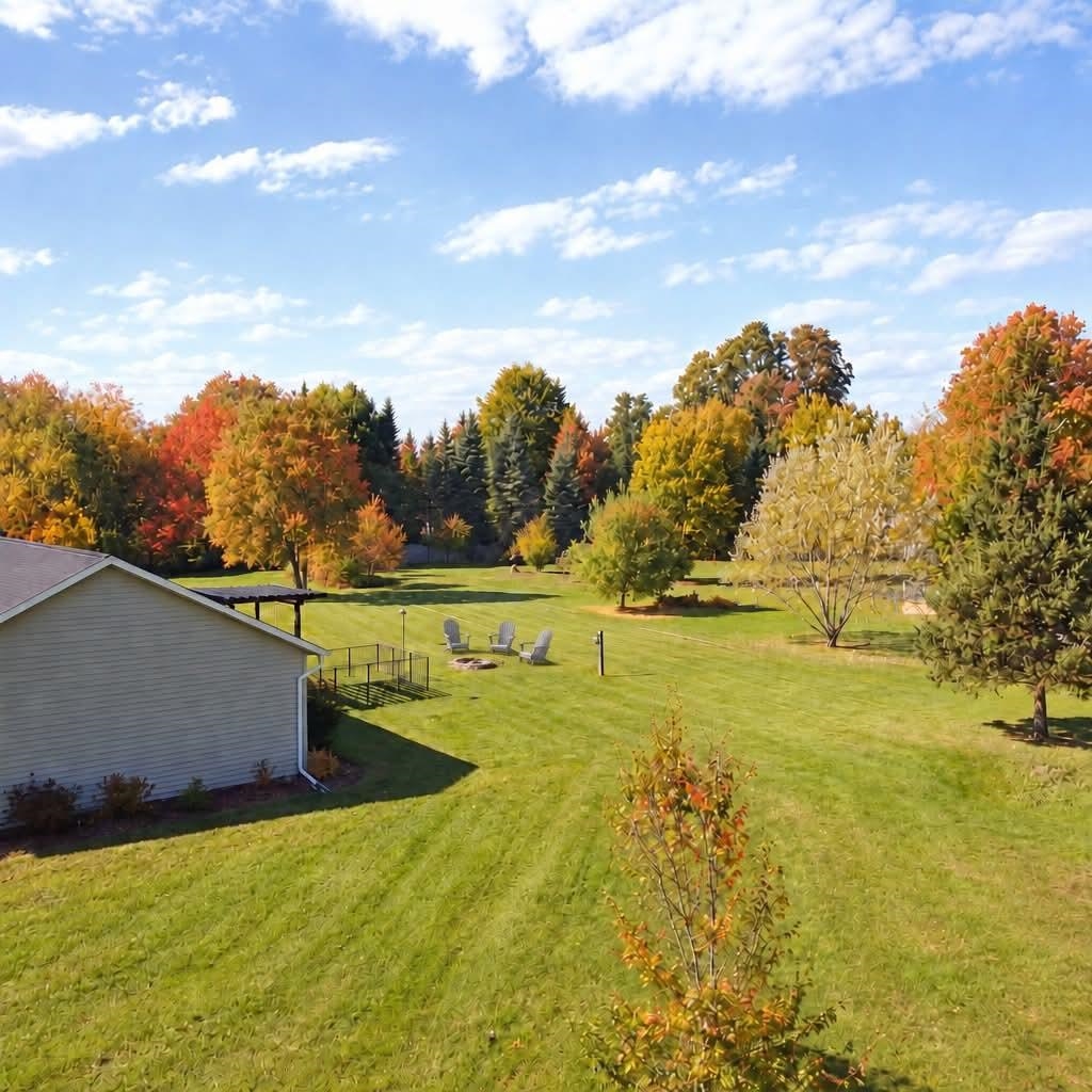 Spacious backyard lawn with a fire pit, outdoor seating, and colorful autumn trees.