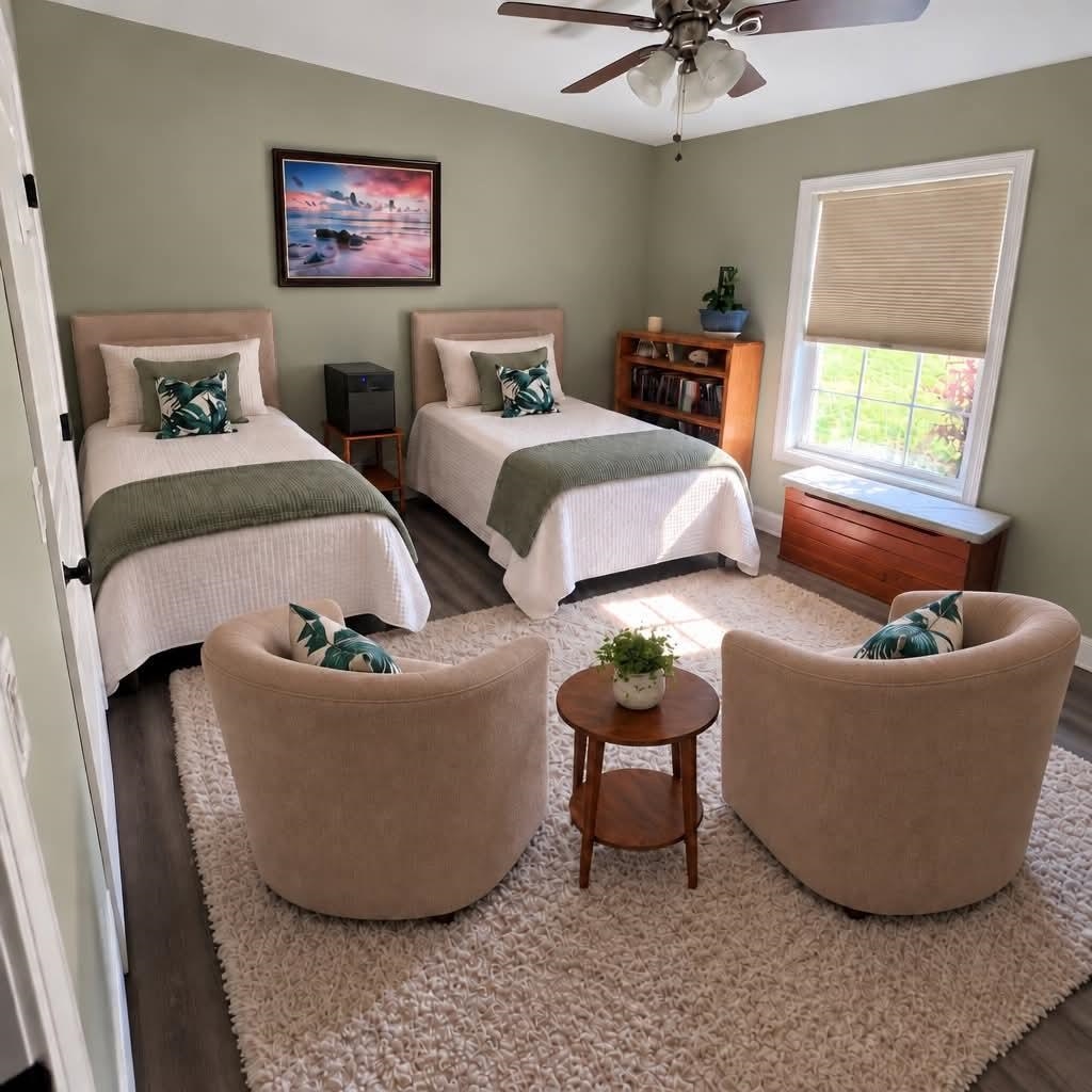 Bedroom with two twin beds, a seating area, and a large window.