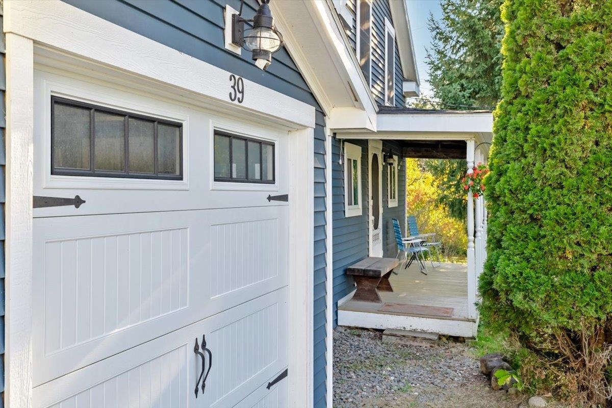 Blue house exterior with white garage door marked 39 and a covered porch with chairs.