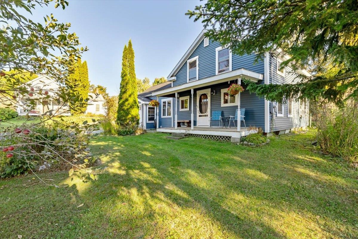 Blue two-story house with a covered porch, white trim, and a broad lawn.