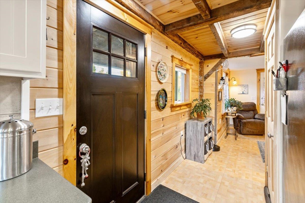 Wood-paneled entry hall with a dark front door and a view of the sitting area.