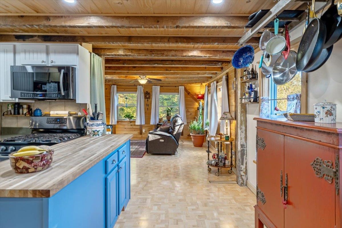 Kitchen with blue cabinets, wood countertops, exposed beams, and an adjoining living area.