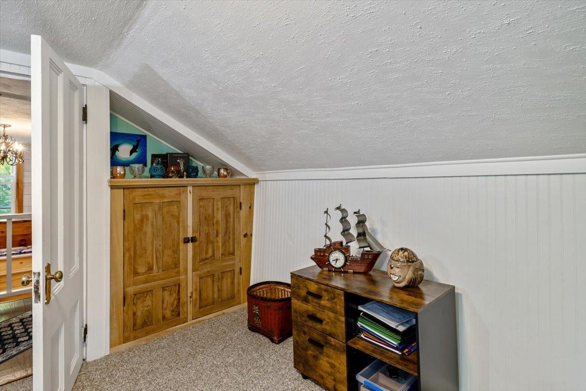 Finished attic room with built-in wooden cabinets and a dresser topped by a model ship.