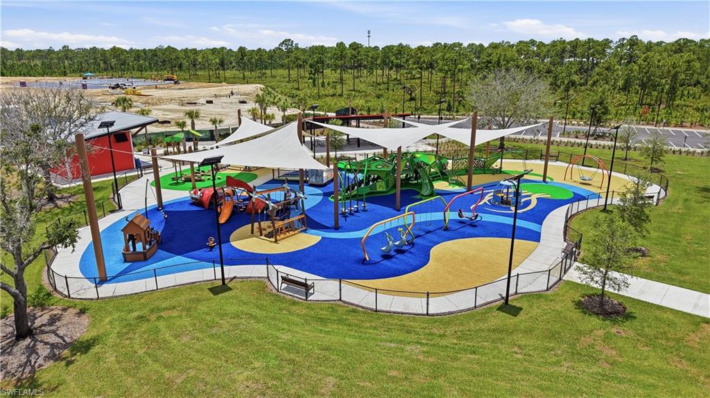 Community playground with colorful climbing structures, slides, swings, and shade sails.