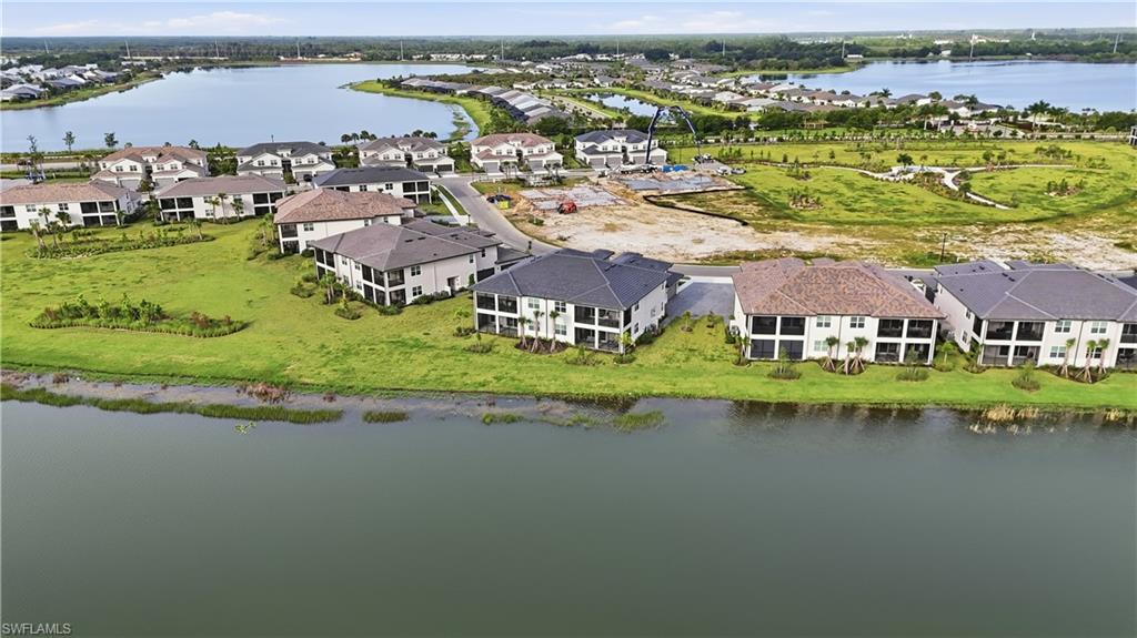 Aerial view of homes along a waterway, with lakes and a construction site beyond.