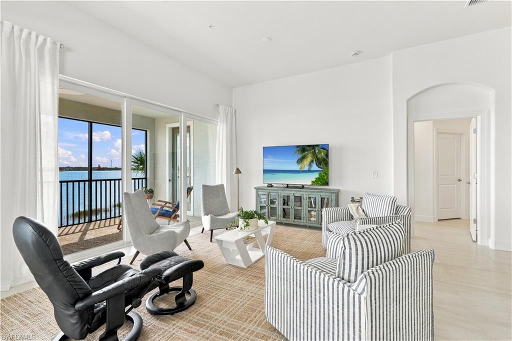 Furnished living room with sliding glass doors opening to a balcony overlooking the water.