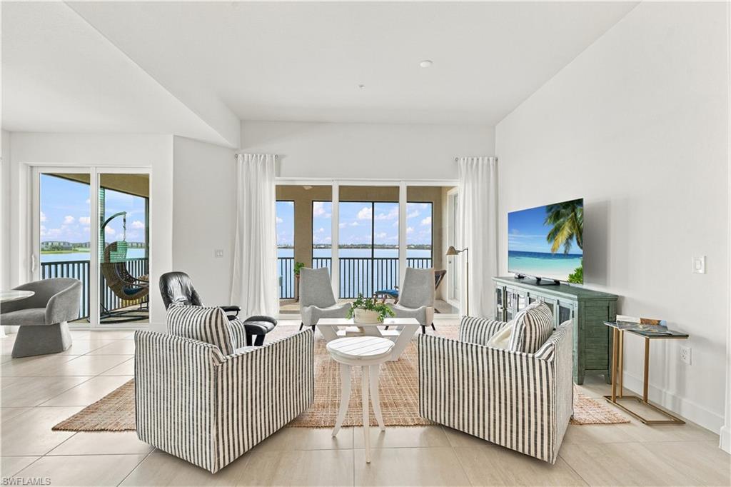 Staged living room with striped seating and sliding doors opening to a water-view balcony.