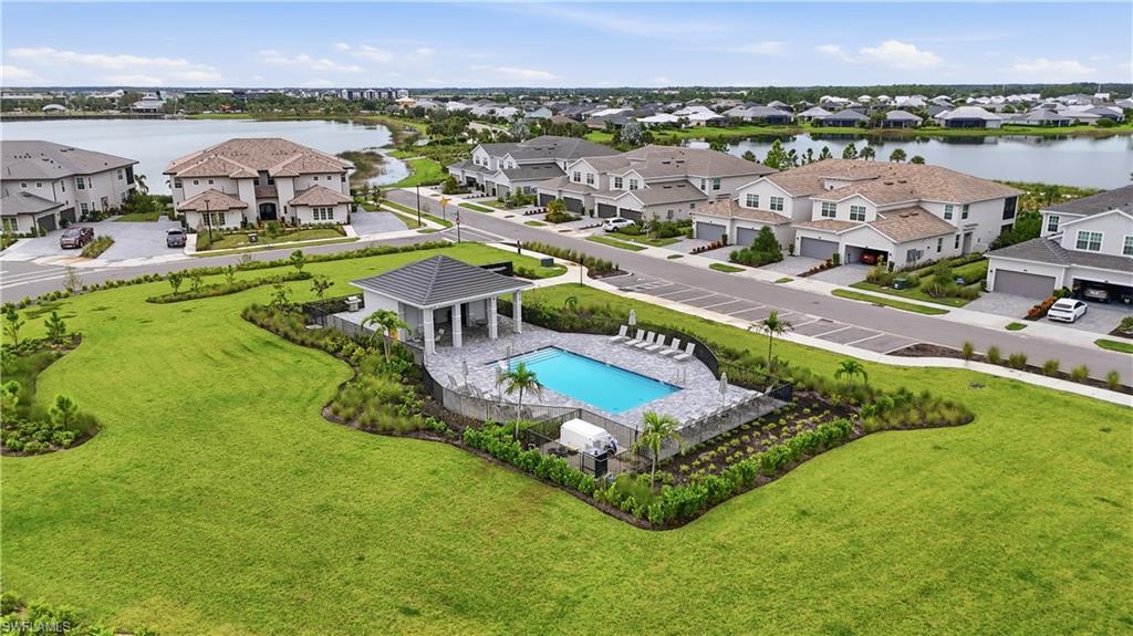 Aerial view of a landscaped community pool surrounded by homes and lakes.