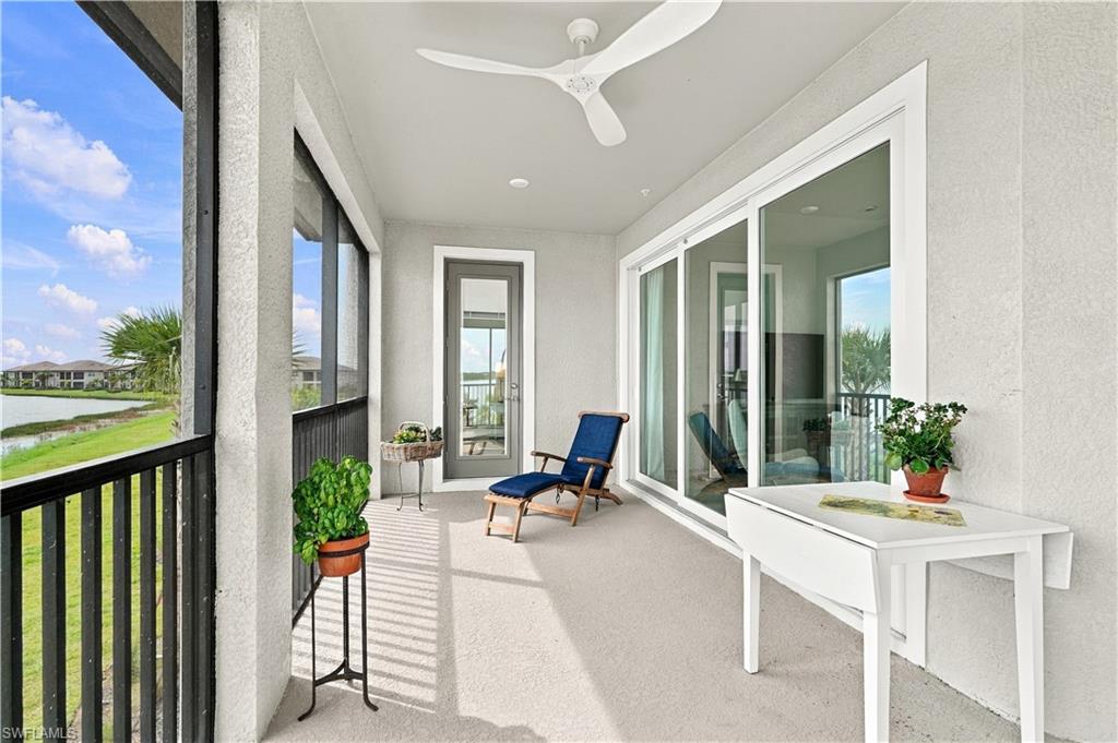 Screened lanai with a blue lounge chair, potted plants, and water visible beyond the railing.