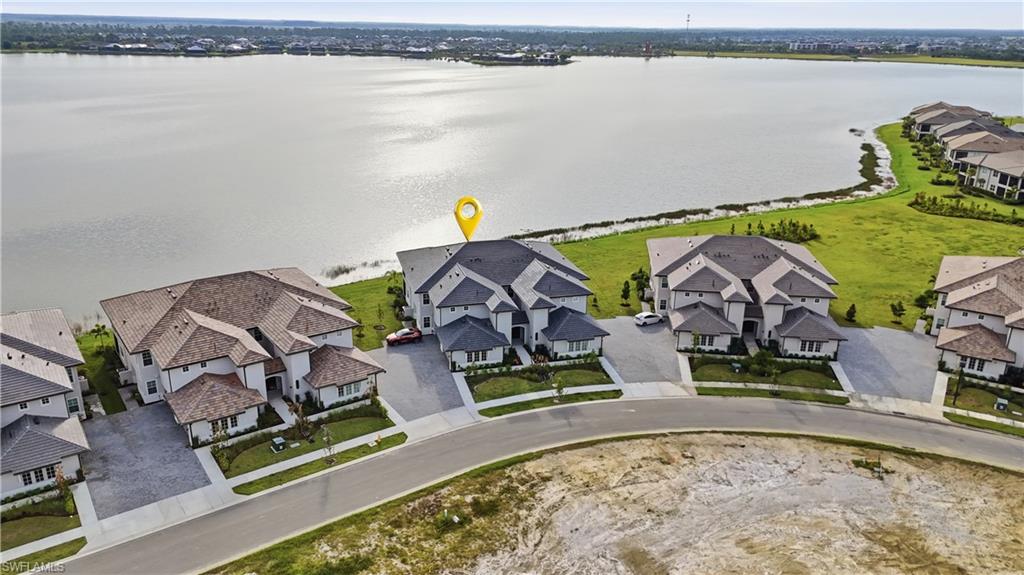 Aerial view of a two-story home beside a broad body of water, marked with a yellow location pin.