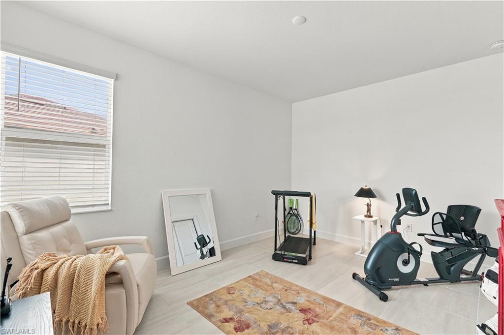 Exercise room with a stationary bike, treadmill, and cream recliner beside a window.