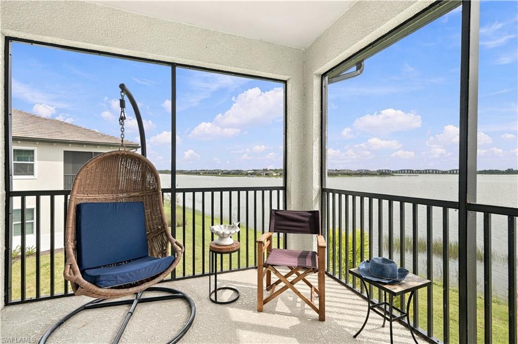 Waterfront balcony with a hanging wicker chair and seating overlooking the water.