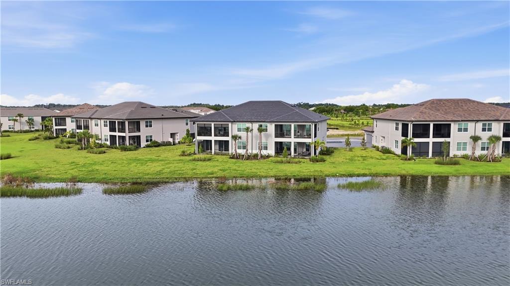 Aerial view of modern two-story residences beside a pond and landscaped lawns.