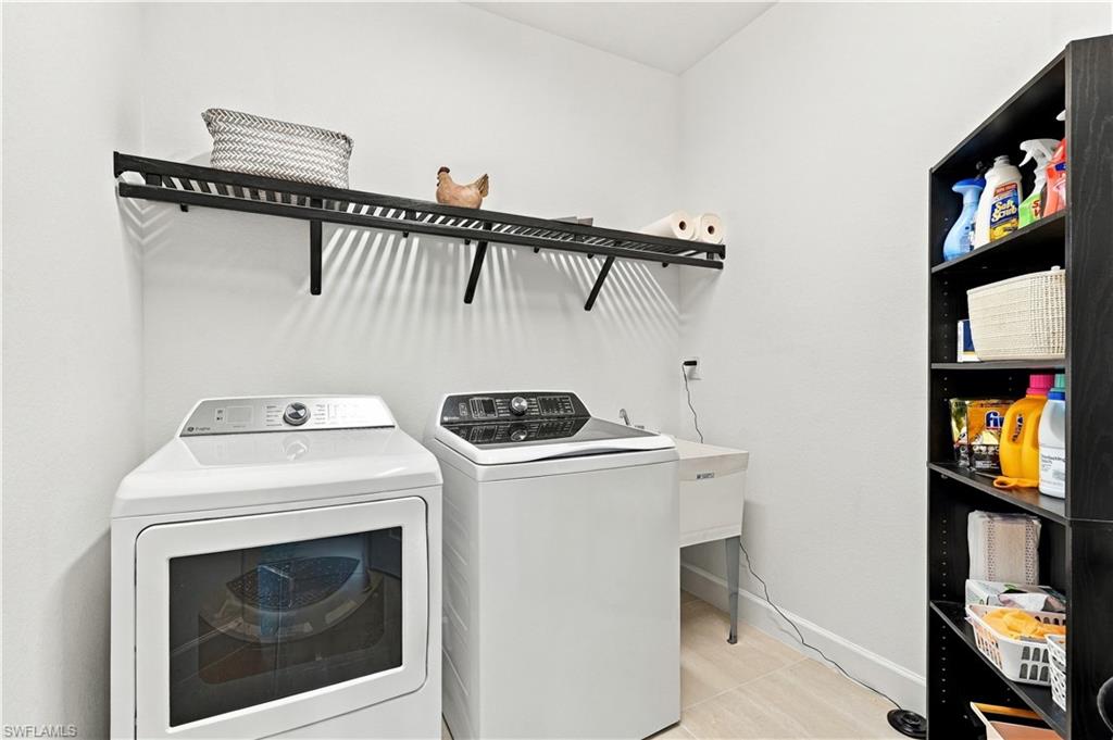 Laundry room with washer and dryer, utility sink, and open shelving for cleaning supplies.