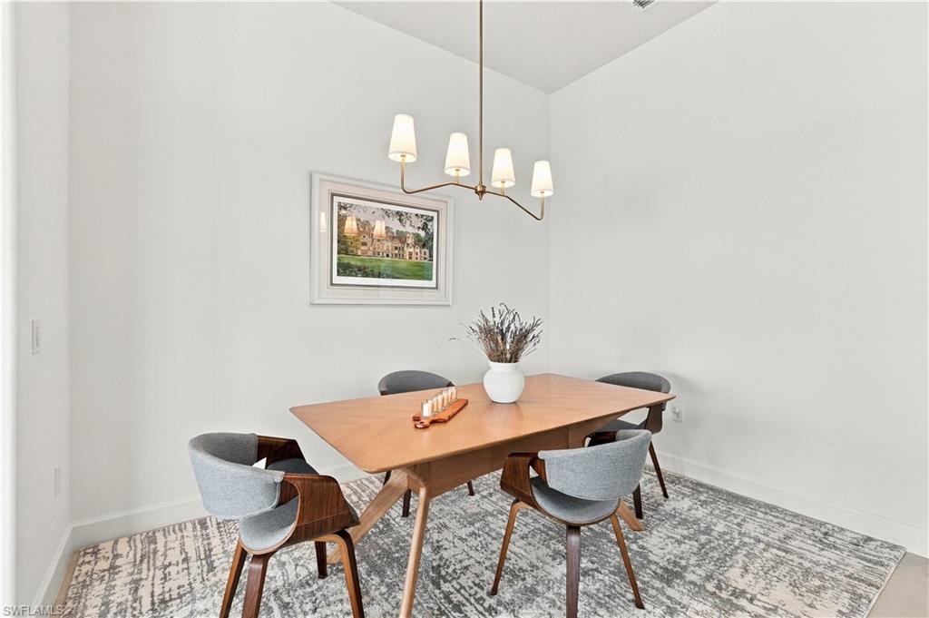 Dining room with a wood table, upholstered chairs, and a modern chandelier.