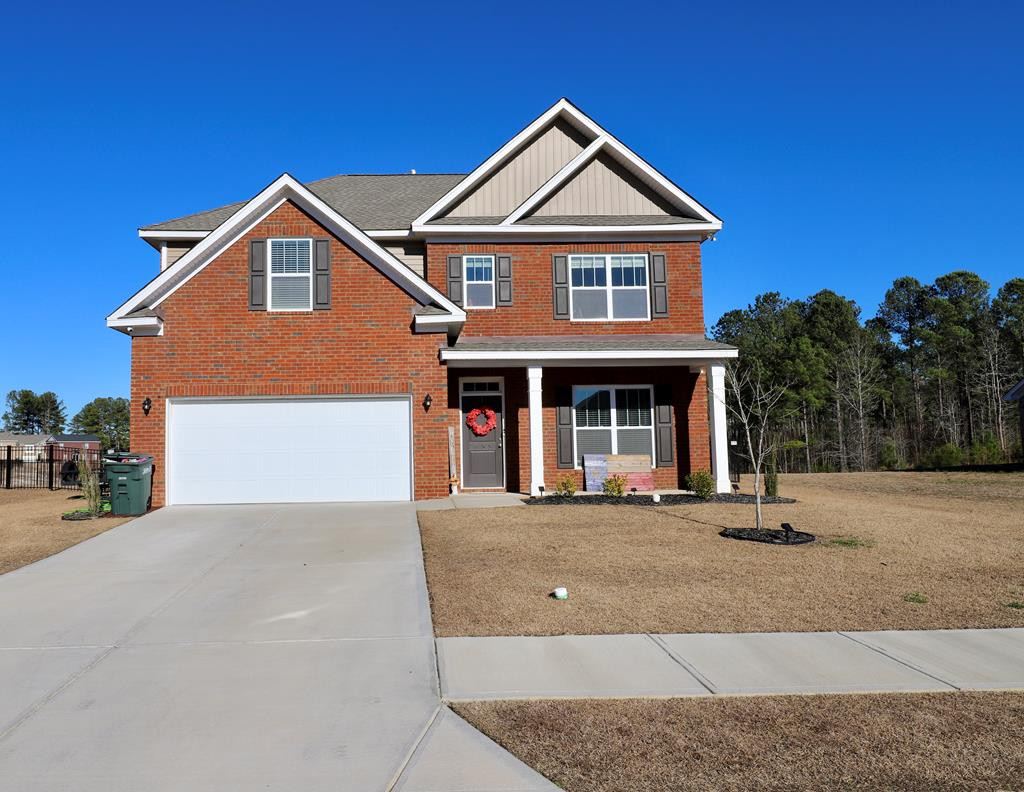 Two-story brick house with a double garage, covered porch, and red wreath on the front door.